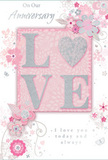 This anniversary card is shown close up, revealing a gentle celebration of enduring romance in a palette of soft pastel pinks and silvery greys, reminiscent of a delicate bouquet waiting on a Romford windowsill. At the centre, the word LOVE appears in raised, velvety glitter, the letters softly curved and light-catching. The O is transformed into a shimmering silver heart, subtly textured so it seems to glow against the blush-toned background. Surrounding this focal word, clusters of delicate blooms in blush, mauve, and muted ivory unfold with a dreamy, watercolour softness. Each petal is edged with fine lines and whisper-light shading, suggesting both careful craftsmanship and the gentle touch of a florist arranging fresh stems for local delivery across Romford. Slender vines curl and loop between the flowers, while tiny flourishes-petals that seem to float, swirling tendrils, and discreet butterflies-add movement and a hint of whimsical charm, like a garden in early spring. The main sentiments, On Our Anniversary and I love you today and always, are printed in graceful, understated scripts that arc across the card like ribbon threaded through a bouquet. Nothing in the design feels heavy or overly ornate; instead, it carries a sense of cherished intimacy, as if chosen from a favourite Romford shop to mark a shared journey that is both tender and enduring, ready to be placed beside fresh flowers on the anniversary table.